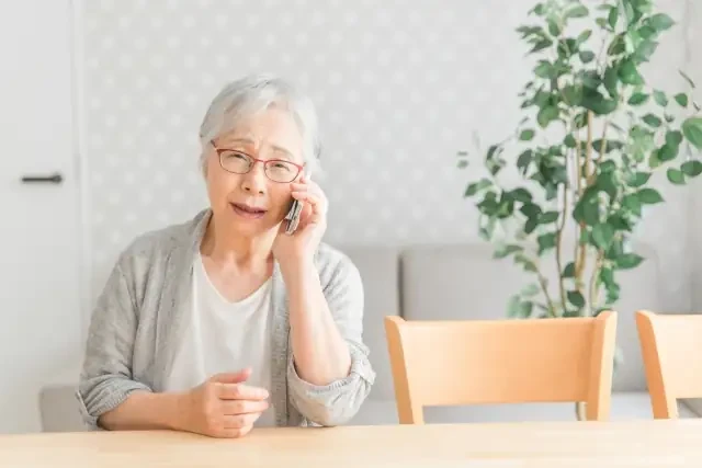 電話をする一人暮らしの高齢女性
